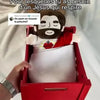 A red box containing a white plush toy of Jesus with a red cloth, set against a light background.