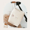 A quilted white baby diaper caddy organizer hanging from a black stroller strap mount.