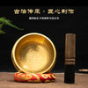 Handmade copper singing bowl with a wooden mallet resting on a red fabric.