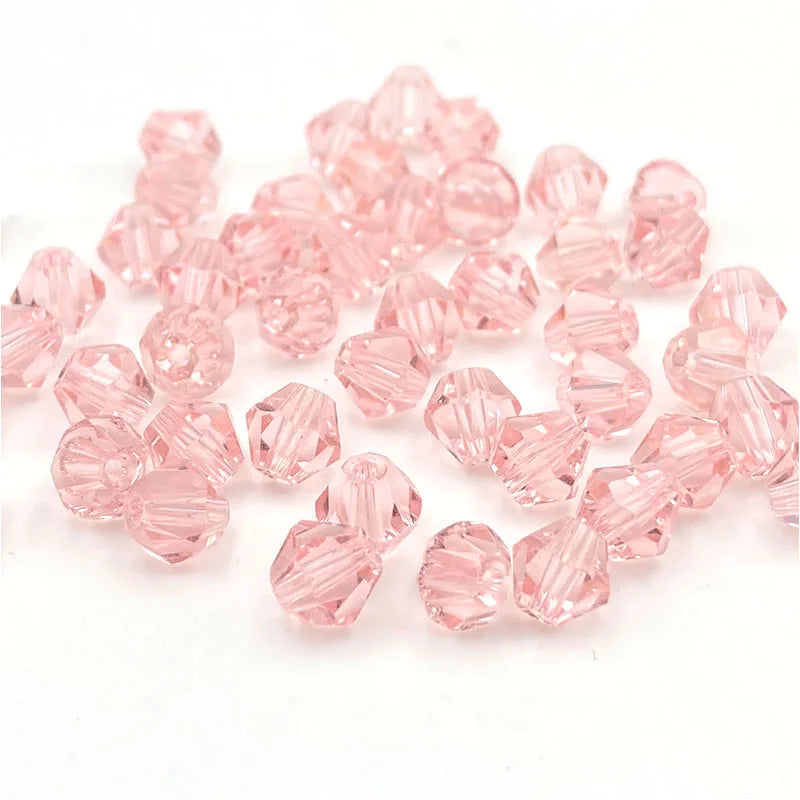 A pile of pink faceted bicone crystal glass beads for jewelry making.