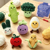 A collection of seven crocheted amigurumi animals including a cactus, broccoli, egg, strawberry, and corn.