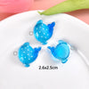 Blue resin charm shaped like a playful sea creature on a white plate.