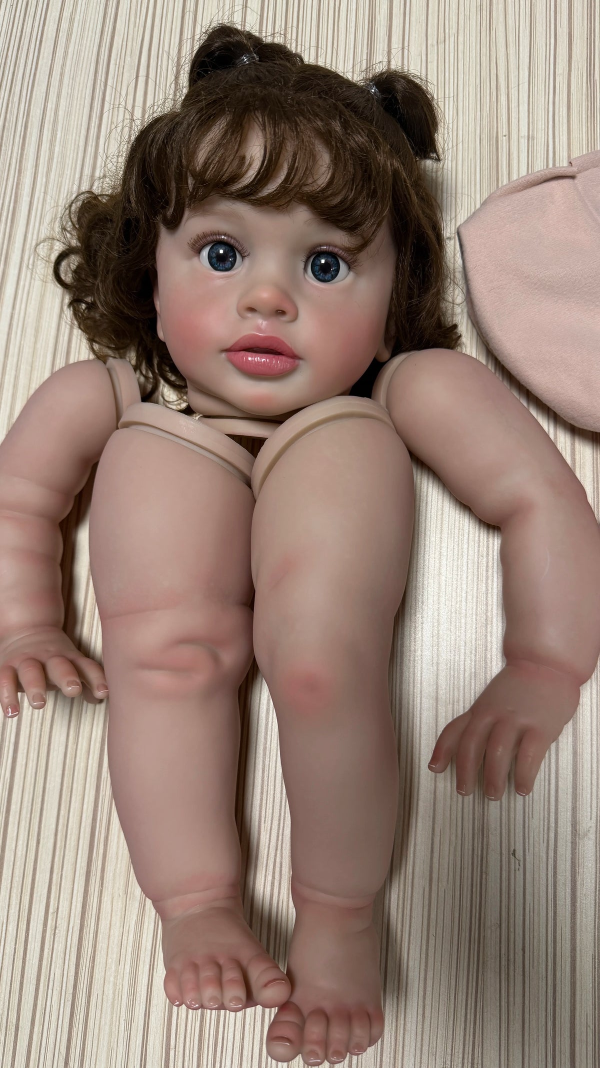 A lifelike reborn baby doll kit featuring painted vinyl parts with brown hair and rosy features.