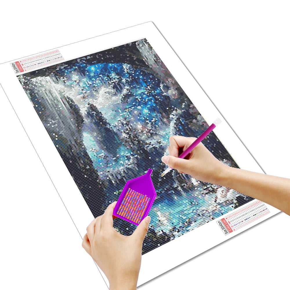 A hand is painting a scenic landscape using a purple tool on a 5D Diamond Painting kit.