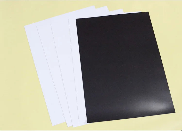 A stack of white and black flexible magnetic dry erase boards.