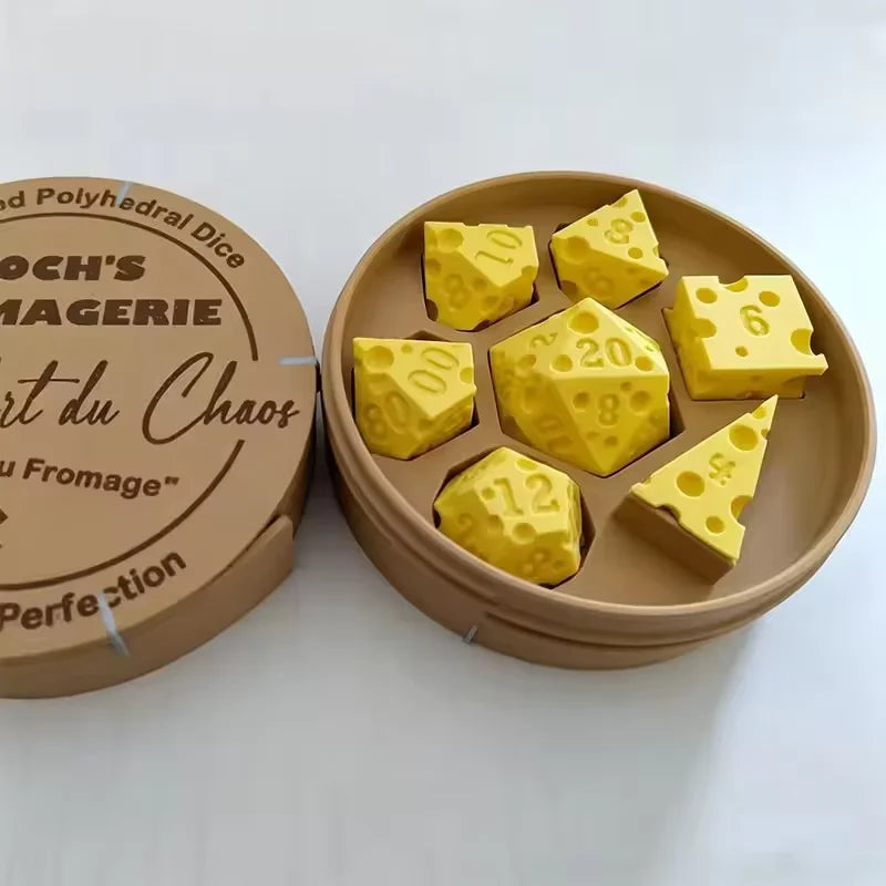 A set of yellow cheese dice cubes is displayed in an open cardboard container with a wooden carrying case nearby.