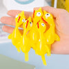 A hand holds a group of yellow, squishy, chicken-shaped toys with orange details.