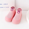 A pair of pink knitted soft sole sock shoes for babies and toddlers with purple accents.