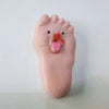 A pink silicone foot with a tongue sticking out, used as a fidget toy for stress relief.