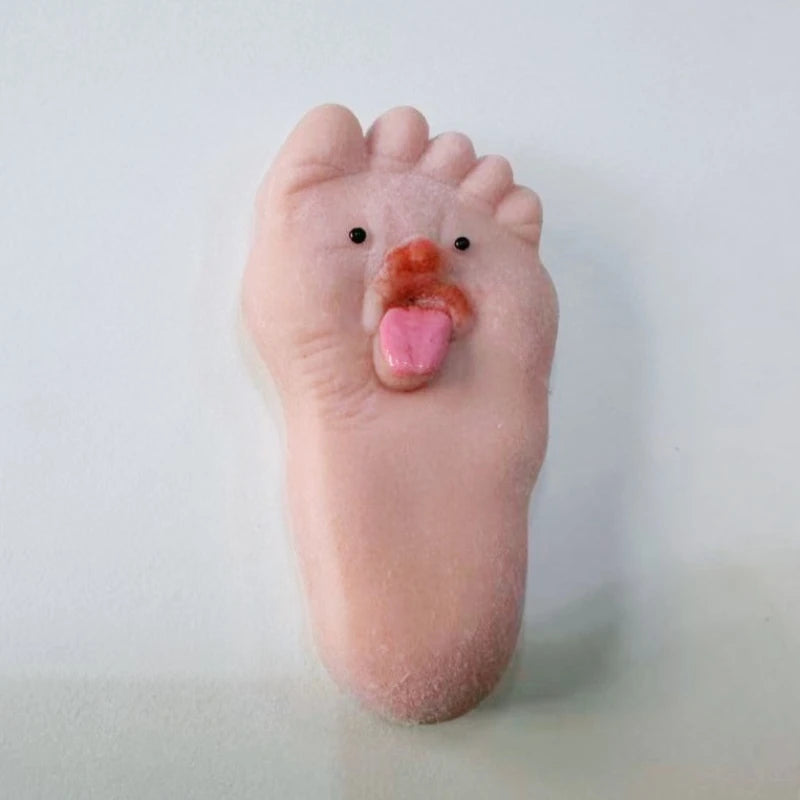 A pink silicone foot with a tongue sticking out, used as a fidget toy for stress relief.