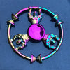 A colorful metal fidget spinner featuring a central disc and four figure components, displayed against a blue background.