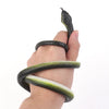 A hand is holding a realistic snake prank toy with a string and clip, showing its texture and form.