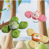 A set of pink and green spinning suction cup bath toys for toddlers floating in the air against a bright outdoor background.