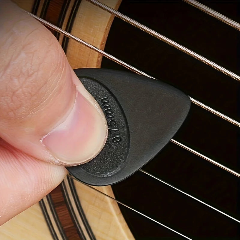 A hand holds a black guitar pick with an anti-slip grip, showing the pick's shape and size.