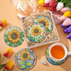 A set of floral diamond painting coasters featuring yellow, pink, and purple flowers displayed with a metal holder and an ora