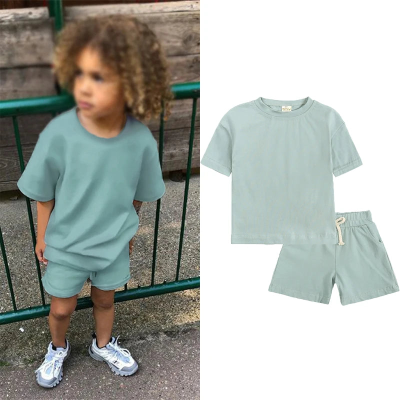A young child models a mint green short sleeve top and matching shorts from a kids' summer tracksuit set.