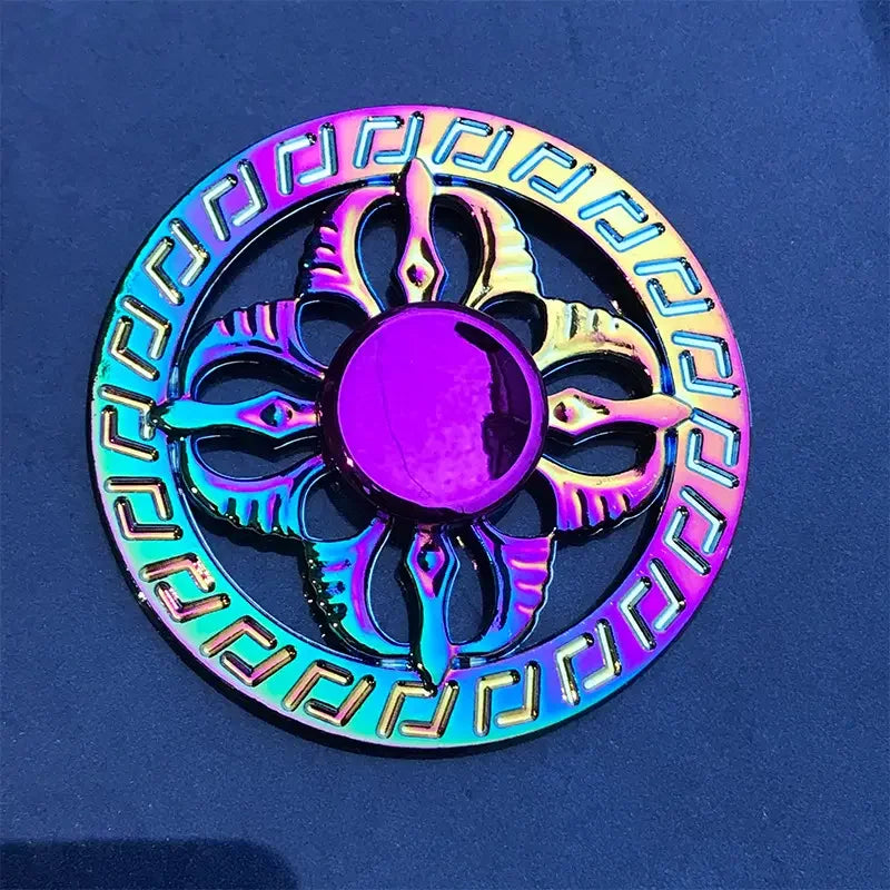 A colorful metal fidget spinner with intricate patterns and a central disc, displayed against a dark blue background.