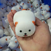 A hand holds a white squishy toy shaped like a dog noodle with orange accents, surrounded by many similar toys.