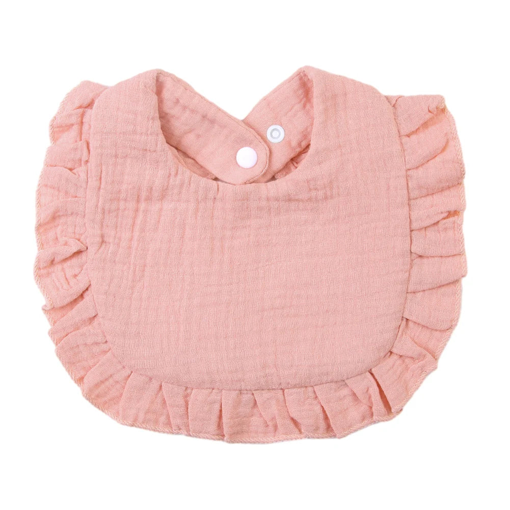 A light pink ruffled muslin cotton baby bib with an adjustable snap closure.