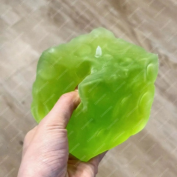 A hand holds a translucent, light green frosted matte jumbo stress ball against a neutral background.