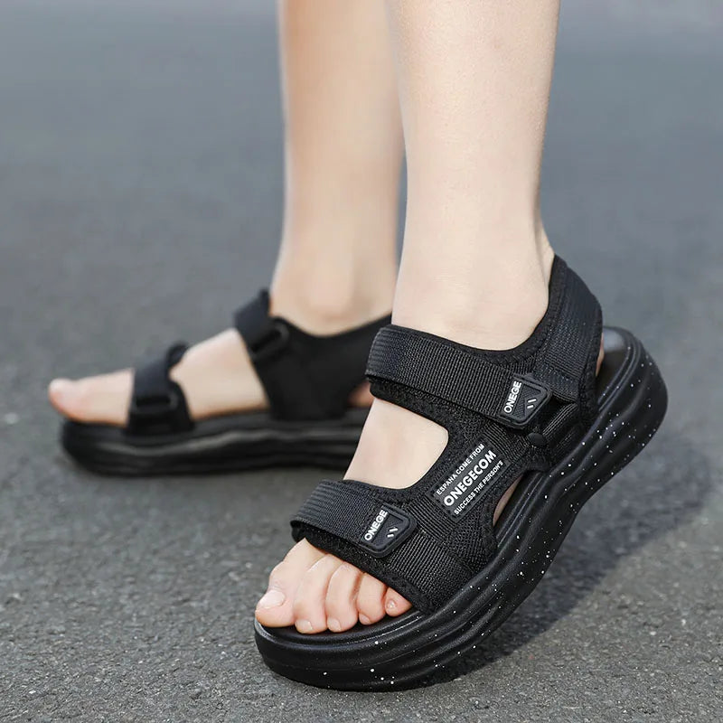 A pair of black Onedge boys' non-slip summer sport sandals worn by a person.