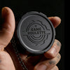 A hand holds a black metal fidget spinner with the text GAME ROULETTE engraved on the top surface.