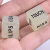 A hand holds two translucent dice labeled TOUCH and KISS from a glow-in-the-dark couples' love game