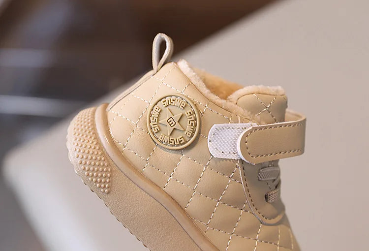 A light beige toddler winter snow boot with a quilted texture and a soft sole, featuring a loop closure.