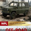 A dark olive green 1/12 scale 4WD off-road truck is shown driving through a muddy, rugged terrain.