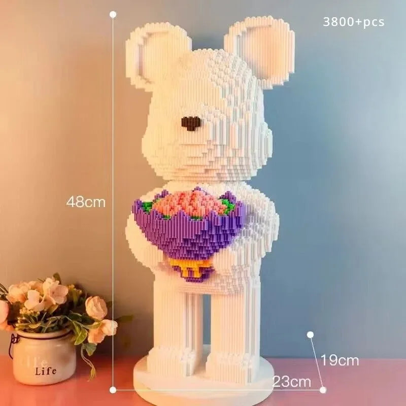 A white bear sculpture made of building blocks with pink and purple flowers, standing on a base.