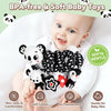 A baby is holding a black and white patterned soft toy rattle for sensory play.