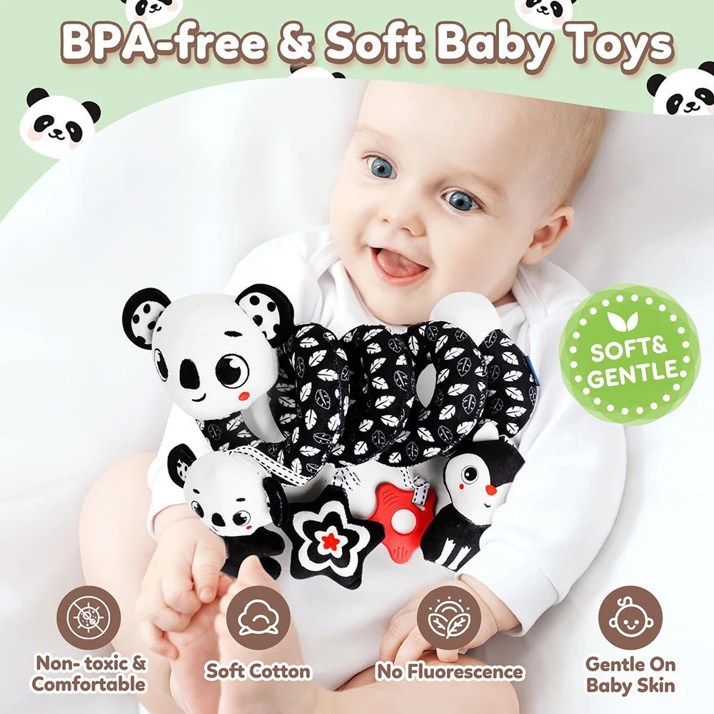 A baby is holding a black and white patterned soft toy rattle for sensory play.