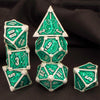 A set of seven green and silver metal polyhedral dice, including a d20 and a pyramid shape, displayed on a dark background.