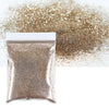 A small bag of holographic fine glitter powder scattered next to a pile of the same glitter.