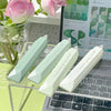 A pack of four light green and white rotating double-sided adhesive dot tape glue rollers displayed on a laptop keyboard.