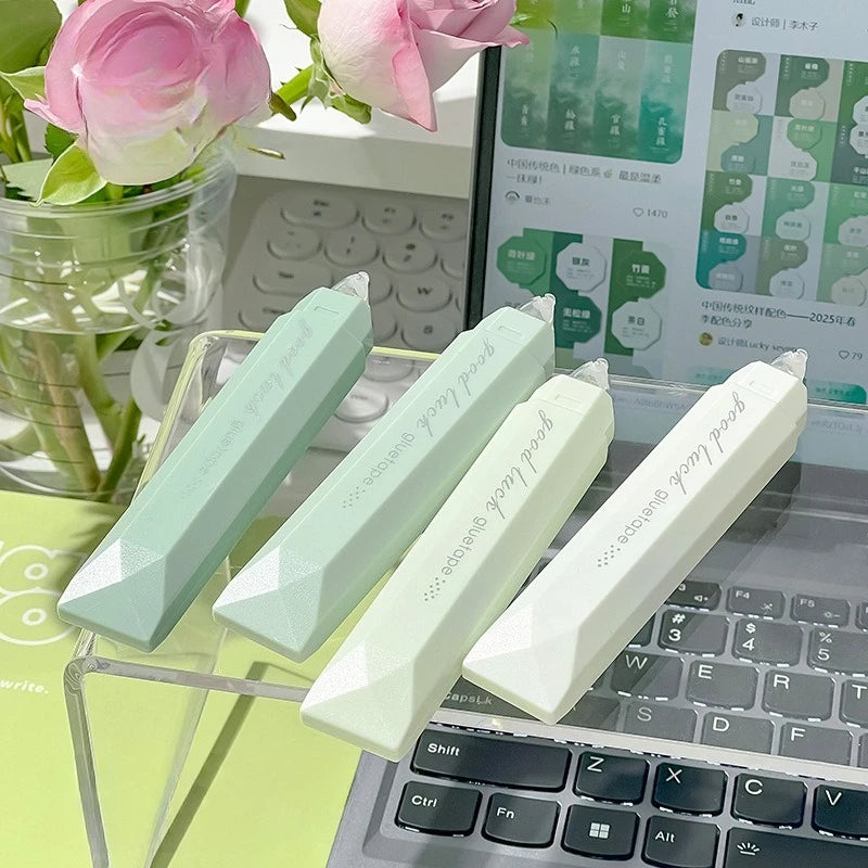 A pack of four light green and white rotating double-sided adhesive dot tape glue rollers displayed on a laptop keyboard.