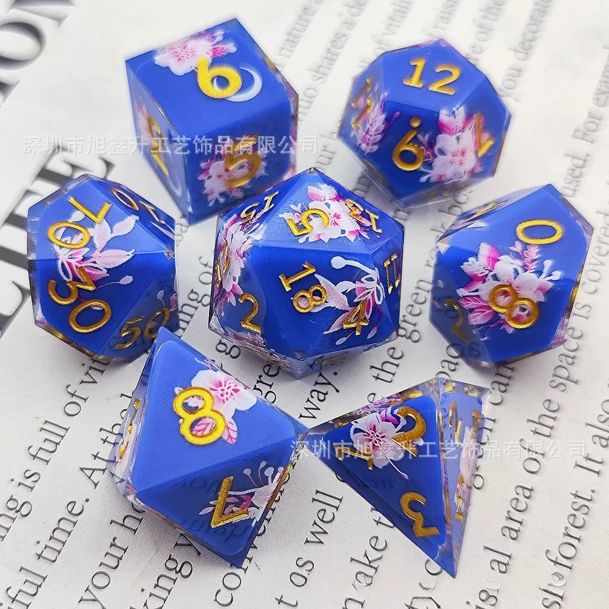 A set of blue resin dice featuring a black kitten design with pink and yellow floral accents.