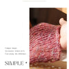A close-up of a knitted sweater cuff in a deep pink color showing fine glaze texture and petal edge detail.