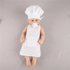 A baby doll dressed in a white chef hat and apron for pretend play