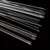 A collection of ultra-fine metal beading needles arranged diagonally on a dark surface.