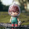 A small blind box figure of a character with reddish hair and green clothing is placed in water on a dark surface.