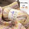 A ball of multi-colored gradient acrylic yarn is shown on a textured fabric background.