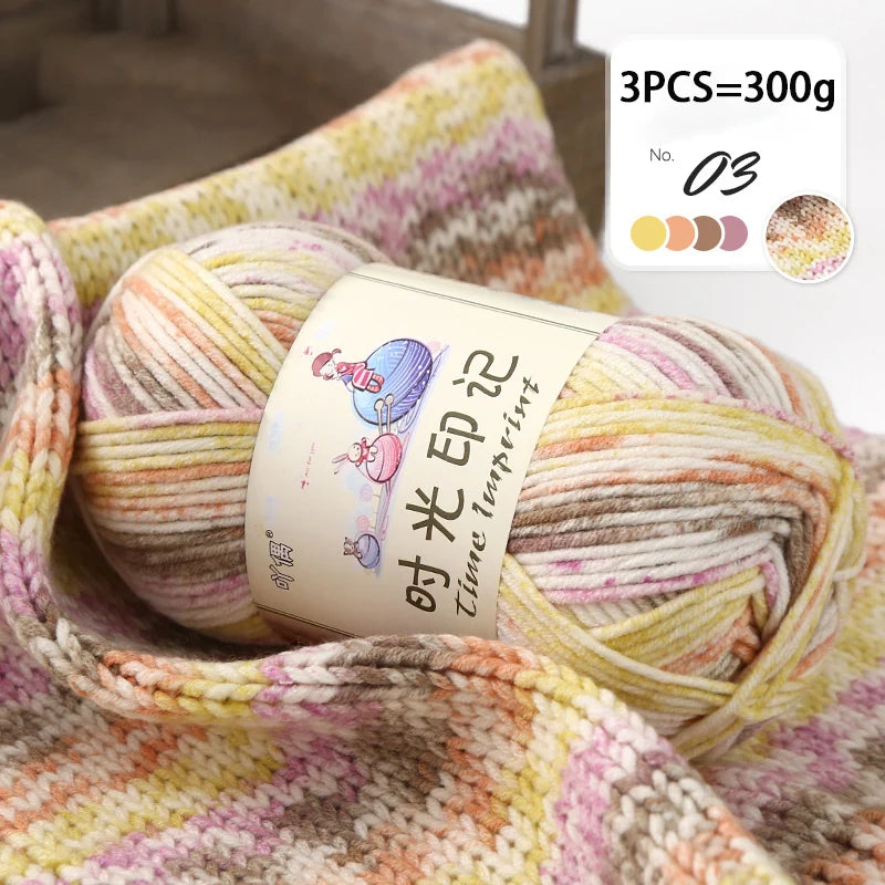 A ball of multi-colored gradient acrylic yarn is shown on a textured fabric background.