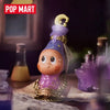 A purple collectible figure blind box with a gold crown and purple attire sits on a wooden surface.