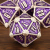 A close-up of a set of premium metal polyhedral dice in purple and silver resting on a wooden surface.