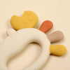 A close-up of a silicone crab-shaped baby teether with various colored, textured parts.