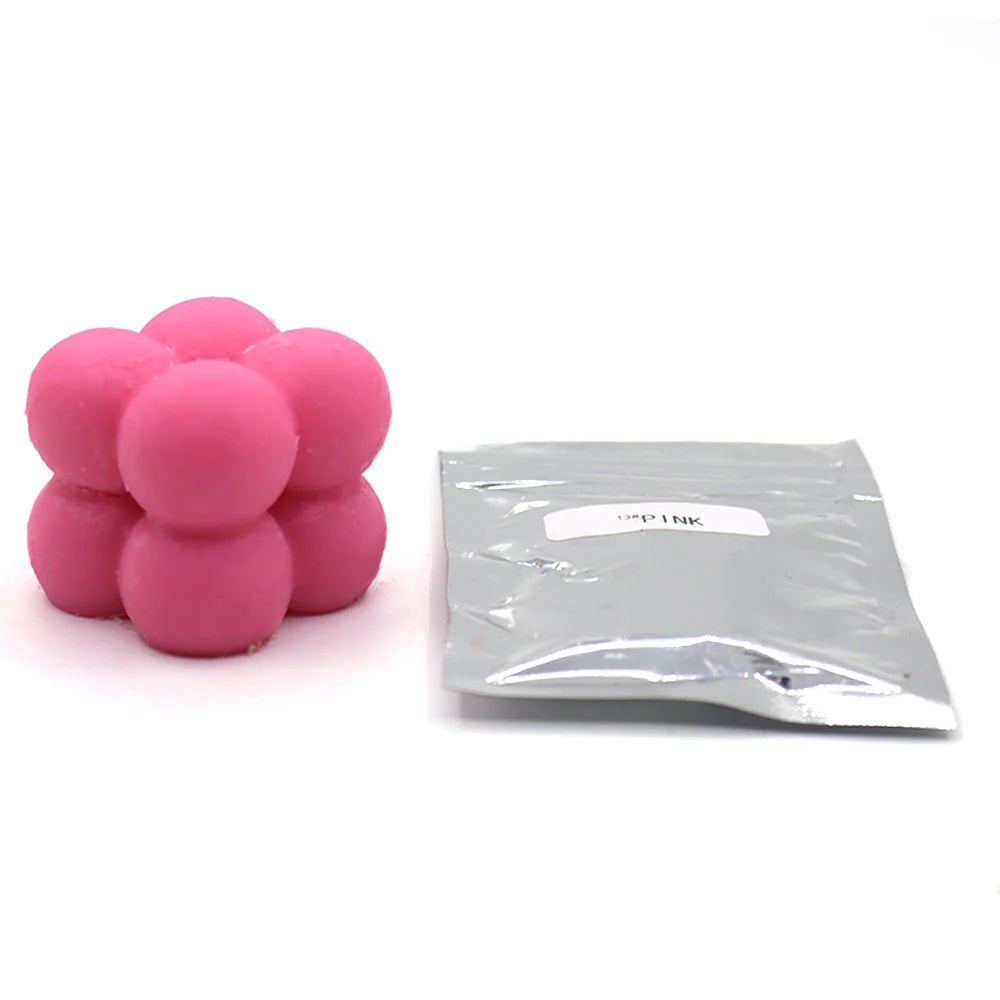 A small plastic bag containing pink candle dye chips for wax.