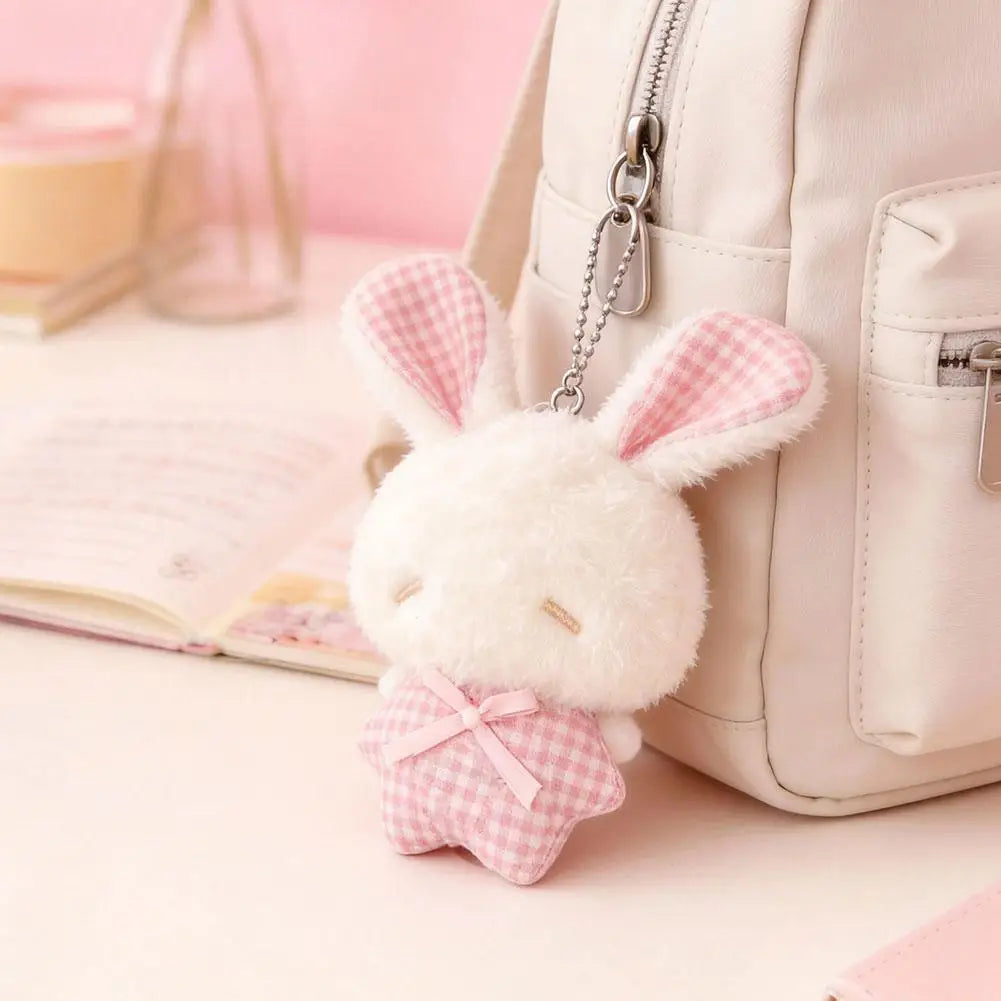 A white plush bunny keychain with pink checkered ears is attached to a light-colored bag.