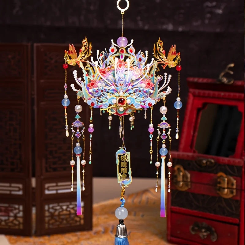 A detailed 3D metal phoenix crown model kit with colorful jewels and dangling elements displayed on a surface.