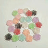 A collection of 20 pink, red, and green rose-shaped resin flowers in various shades arranged on a white background.